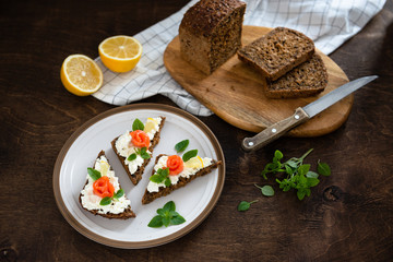smoked salmon sandwich with fresh cream, lemon and basil on white plate. Healthy breakfast concept. Wholegrain bread, copy space