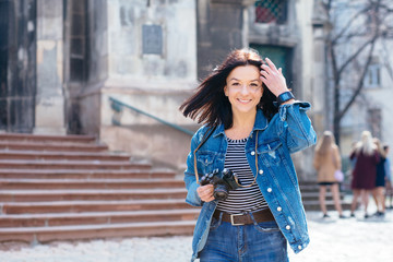 Outdoor spring portrait brunette caucasian woman walking on the street at sunny day, having fun alone, travel concept , young photographer with vintage camera.