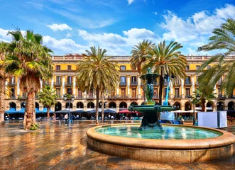 Fotobehang Koninklijk gebied in Barcelona, Spanje. Fontein met standbeelden en hoge palmbomen tussen traditionele Spaanse architectuur op het centrale plein van de oude stad. Zomerlandschap met blauwe lucht en wolken. © Yasonya