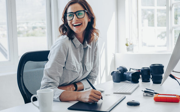 Cheerful female photographer at her office desk