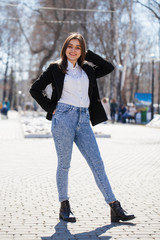 Teen girl in white shirt and blue jeans walks in spring park