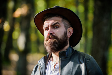 Adventures of cowboy. Man bearded cowboy nature background defocused. Brutal cowboy with long beard. Hipster tourist explore forest. Tourist hunter or gamekeeper. Masculinity and brutality concept