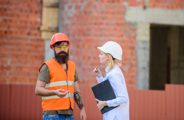 Discuss progress project. Woman engineer and bearded brutal builder discuss construction progress. Construction project management. Building industrial project. Construction industry concept