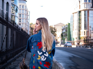 Fototapeta premium cute blonde teen with flowing hair in a denim jacket on the bridge outdoor