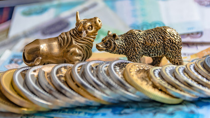 The bronze bull and bear figurines are arranged with paper money and metal coins. Blur background. Symbol and concept of trading on the stock exchange.