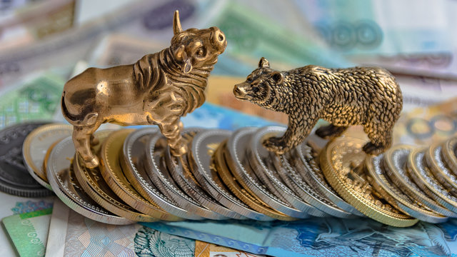 The bronze bull and bear figurines are arranged with paper money and metal coins. Blur background. Symbol and concept of trading on the stock exchange.