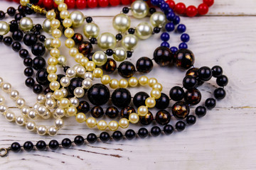 Different beads necklaces on white wooden background