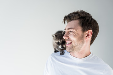 handsome smiling man with cute raccoon on shoulder on grey © LIGHTFIELD STUDIOS