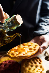 man dressing with olive oil an italian focaccia