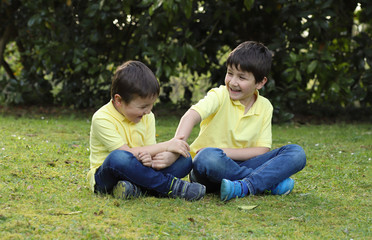 Fototapeta premium niños felices riendo en el jardín haciendose cosquillas 