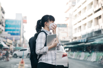 Asian woman wearing face mask coughing because of air pollution in the city