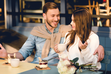 cheerful man looking at happy girlfriend holding cup of coffee