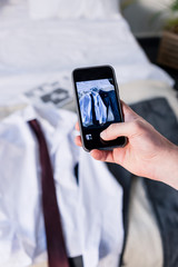 partial view of man taking photo of suite on bedding with smartphone