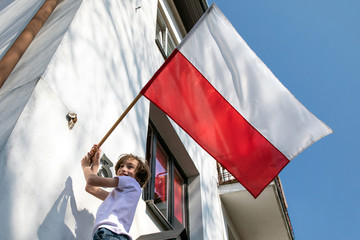 The boy is hanging a flag. Polish National Day of the Third of May, Constitution Day Flag Day, International Labor Day