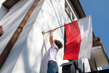 The boy is hanging a flag. Polish National Day of the Third of May, Constitution Day Flag Day,...