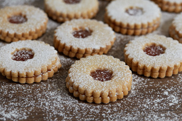 Close up of freshly baked homemade Christmas sugar cookies with jam on a wooden background