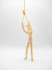Miniature wooden doll is pulling hands to hanging rope and touch gallow noose. 