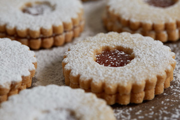 Close up of freshly baked homemade Christmas sugar cookies with jam on a wooden background
