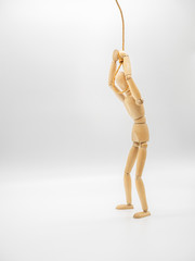 Miniature wooden doll is putting head in the noose of gallows isolated on white. Suicide concept with the hanging rope.