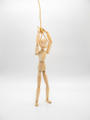Miniature wooden doll is putting head in the noose of gallows isolated on white. Suicide concept with the hanging rope.