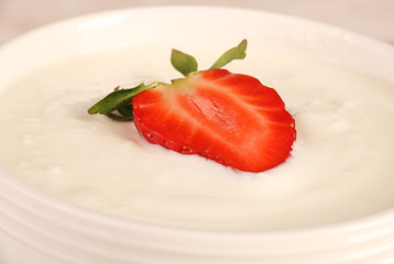 Healthy yougurt with stawberry on the white wooden table, selective focus