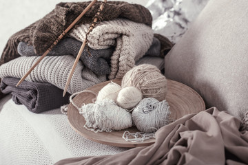 Fototapeta na wymiar Vintage wooden knitting needles and threads for knitting on a cozy sofa with pillows and sweaters