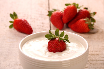 Healthy yougurt with stawberry on the white wooden table, selective focus