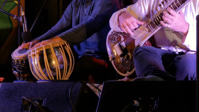 Two men playing traditional Indian tabla drums and sitar on stage of ethnic open air concert. Relaxation, meditative and traditional ethnic music concept