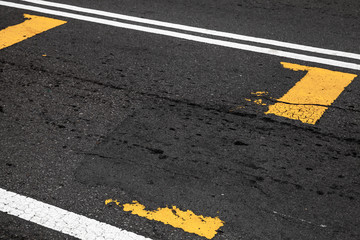 Yellow and white lines over dark asphalt