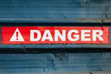 Naklejka premium Danger sign on red tape over blue fence