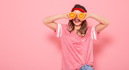 Portrait of a girl with oranges in hand, on a pink background
