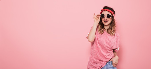 Portrait of hipster girl in glasses on pink background