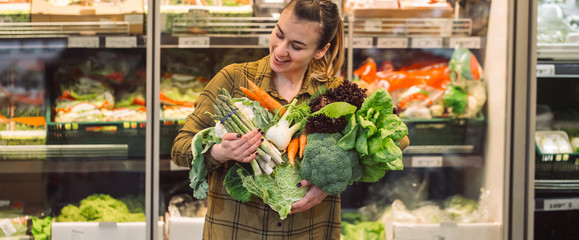 Woman in the supermarket. Beautiful young woman shopping in a supermarket and buying fresh organic...