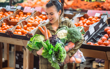 Woman in the supermarket. Beautiful young woman shopping in a supermarket and buying fresh organic vegetables