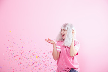 Funny Girl with silver hair gives a smile and emotion on pink background. Young woman or teen girl...