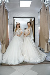 Naklejka premium Happy brides in wedding dresses posing in salon