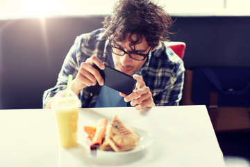 leisure, food, eating and people concept - man with smartphone photographing his lunch at cafe