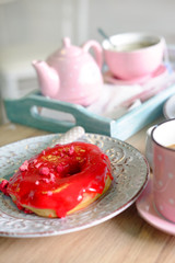 In the cafe. A pink cup of coffee with milk and amazing red donuts on table