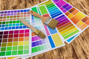 Brushes and paint color palette samples on wooden background, closeup