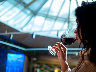 portrait of an attractive girl with beautiful lips who drinks red wine from a glass