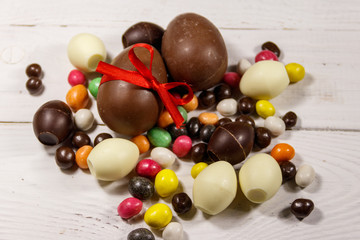 Easter composition with chocolate eggs on white wooden background