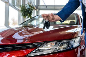 Male hand with keys against new red car