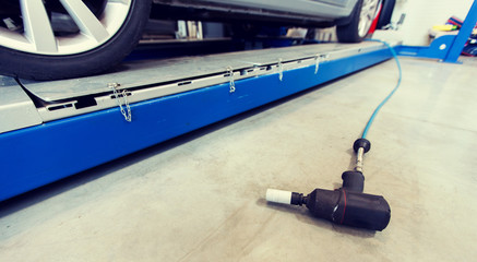 Fototapeta premium auto service, repair and maintenance concept - screwdriver and car on lift at tire shop