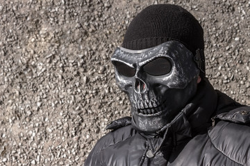 Street criminal in a mask of death and a knitted hat