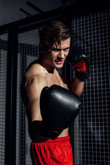 Handsome boxer in black boxing gloves training with smile