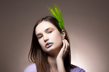 Model with blue lines on lips posing near background with spikelet