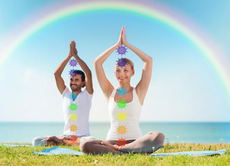 mindfulness, spirituality and outdoor yoga - couple meditating in lotus pose with seven chakra...
