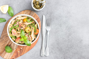 Salad - penne pasta with tomatoes, pesto, basil and lemon. Top view. Copy space. Horizontal.