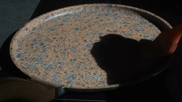 The process of cooking homemade pancakes. The cook grases the hot pan pours pancake dough with ladle. Cooking a fresh breakfast on a sunny morning. Fatty food. Appetizing pancakes baking in a skillet