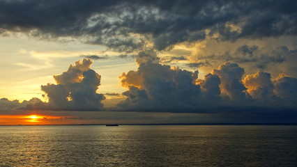 Sonnenuntergang mit gelb angestrahlten und konturenreichen Wolken über dem Meer